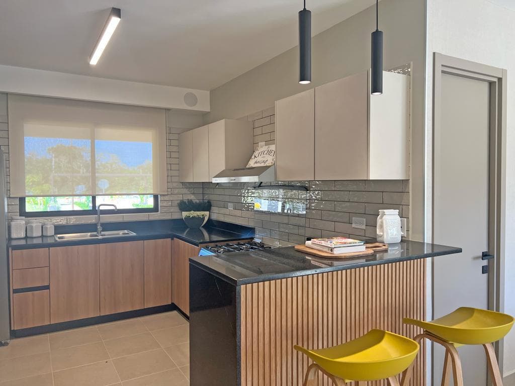 Novo Hogar kitchen with island, dark granite countertop and wood slatted peninsula